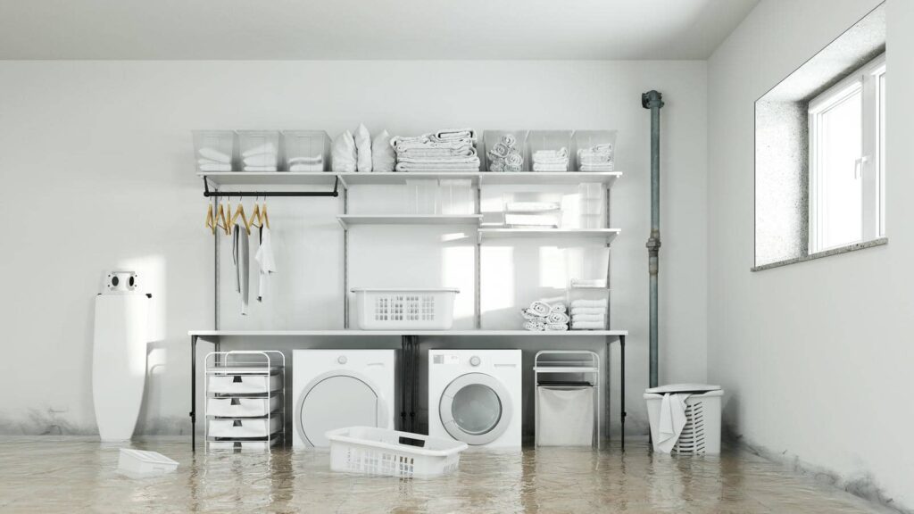 Laundry room flooded with water covering the floor around washing machines and shelves.